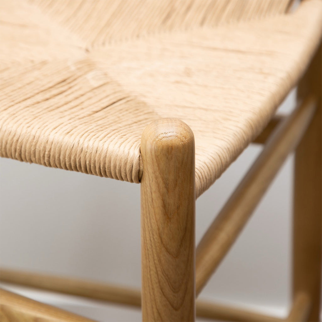 Pic. 1 close-up seat and leg detail of the Frida Counter Stool, blonde. A minimalist counter stool inspired by the mid-mod 1950s Hans J Wegner wishbone chairs with a Y-back design, curving top rail and tapered legs details.