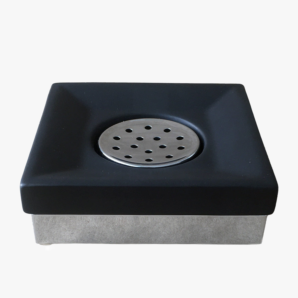 Silhouette Soap Dish, Black. A modern ceramic soap dish featuring a sleek matt black finish, chrome base, and centre drain cover.